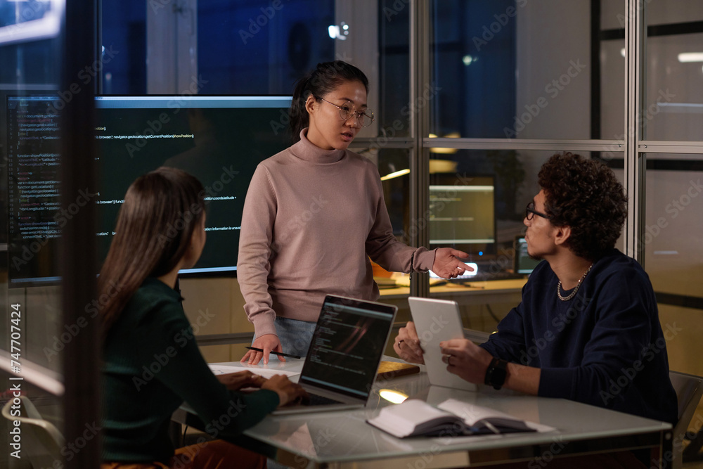 Group of ethnically diverse programmers spending evening in office working together on computer code Group of ethnically diverse programmers spending evening in office working together on computer code