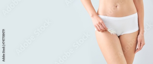 Beautiful young woman in underwear holding soft feather on light background with space for text, closeup. Epilation concept
