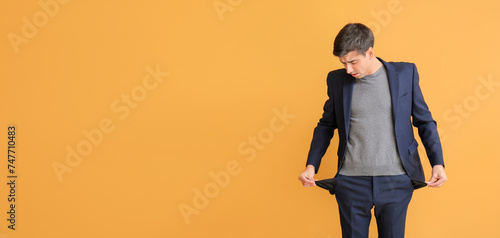 Photos Stressed man with empty pockets on color background