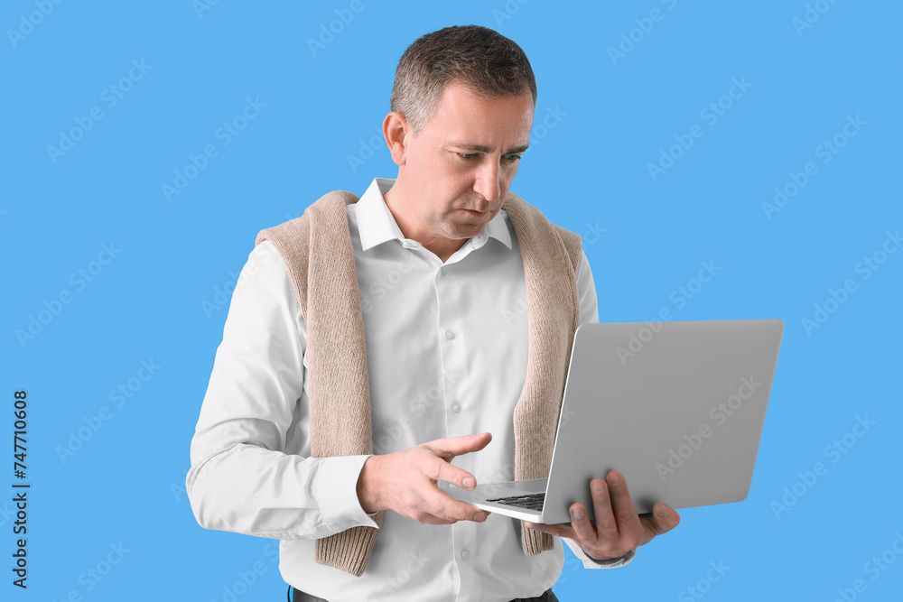 Mature man with laptop on blue background