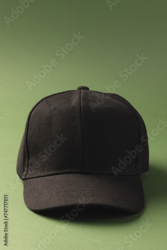 A black baseball cap is positioned against a green background, with copy space