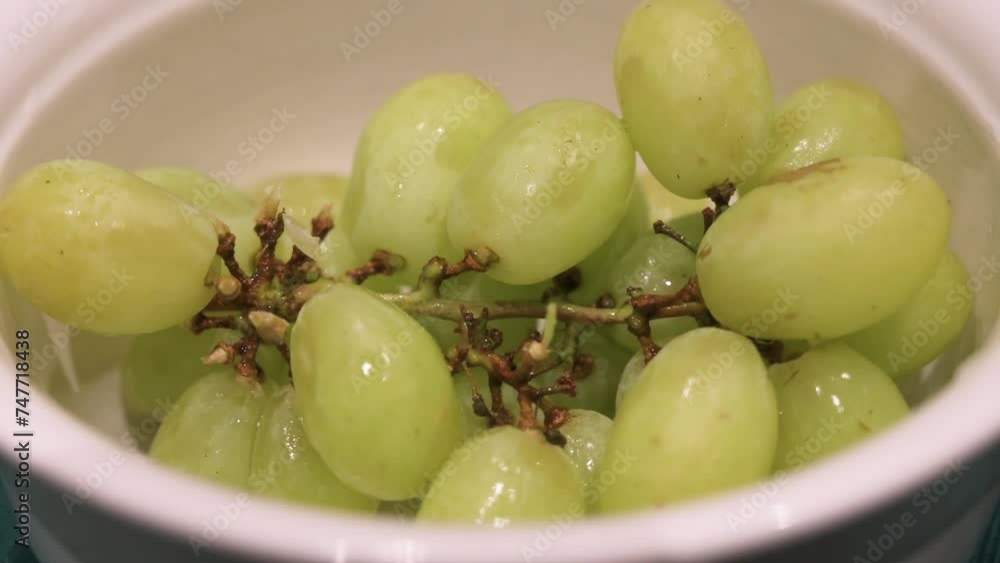 Fresh green grapes, ready to be eaten, are seen in a white bowl. Fresh green grapes, ready to be eaten, are seen in a white bowl.
