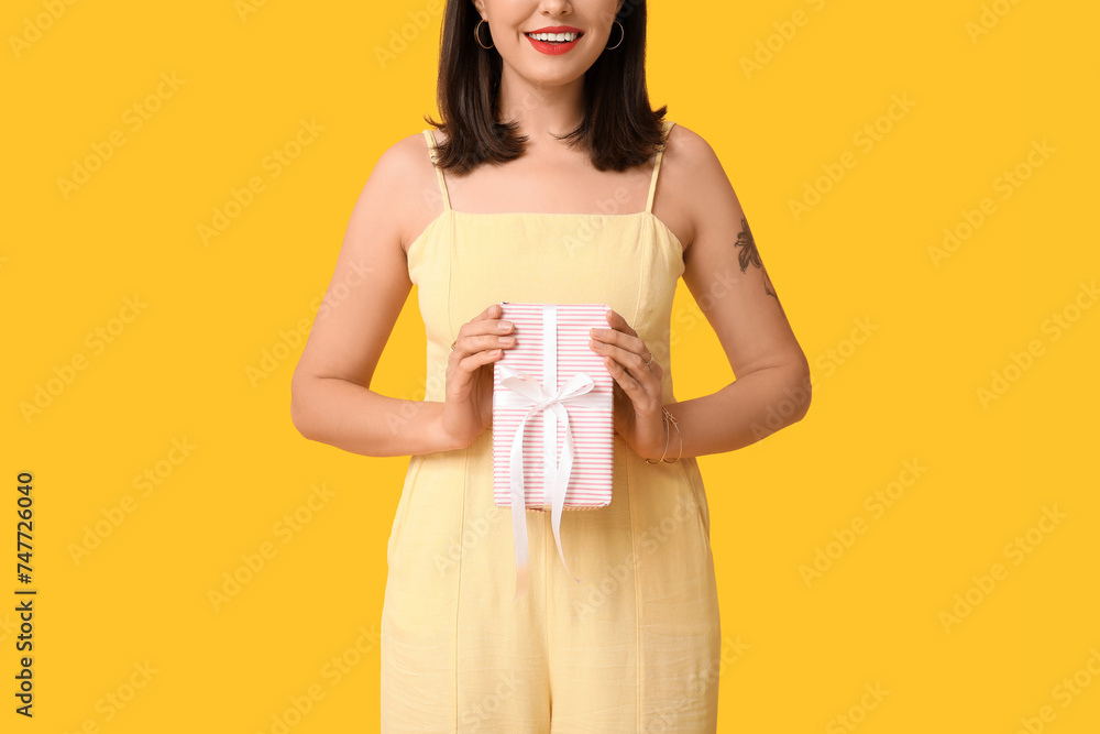 Beautiful young happy woman with gift box on yellow background. Valentine's Day celebration Beautiful young happy woman with gift box on yellow background. Valentine's Day celebration