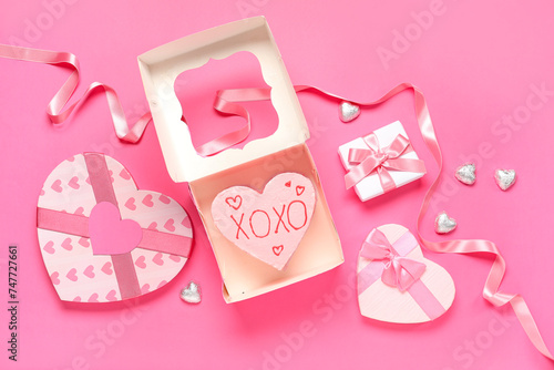 Heart-shaped bento cake with gift boxes and chocolate candies on pink background. Valentine's Day celebration
