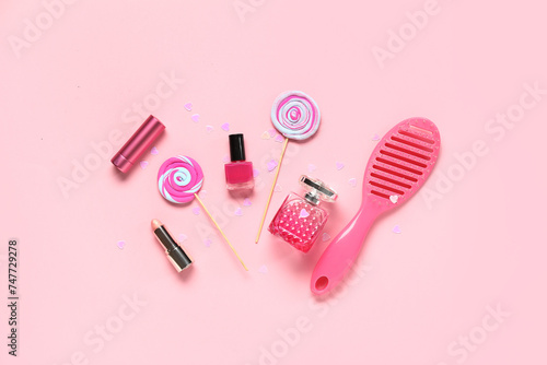 Composition with decorative cosmetics, hair brush and lollipops on pink background. Valentine's Day celebration