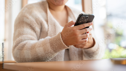 A woman using her smartphone, chatting or reading messages, while sitting at a table in a cafe.