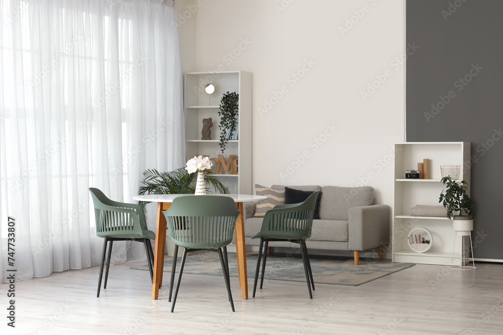 Interior of comfortable living room with table, chairs, houseplants, sofa and shelving unit Interior of comfortable living room with table, chairs, houseplants, sofa and shelving unit
