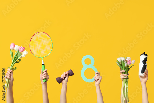 Female hands with paper figure 8, sports equipment and tulips for International Women's Day on yellow background © Pixel-Shot
