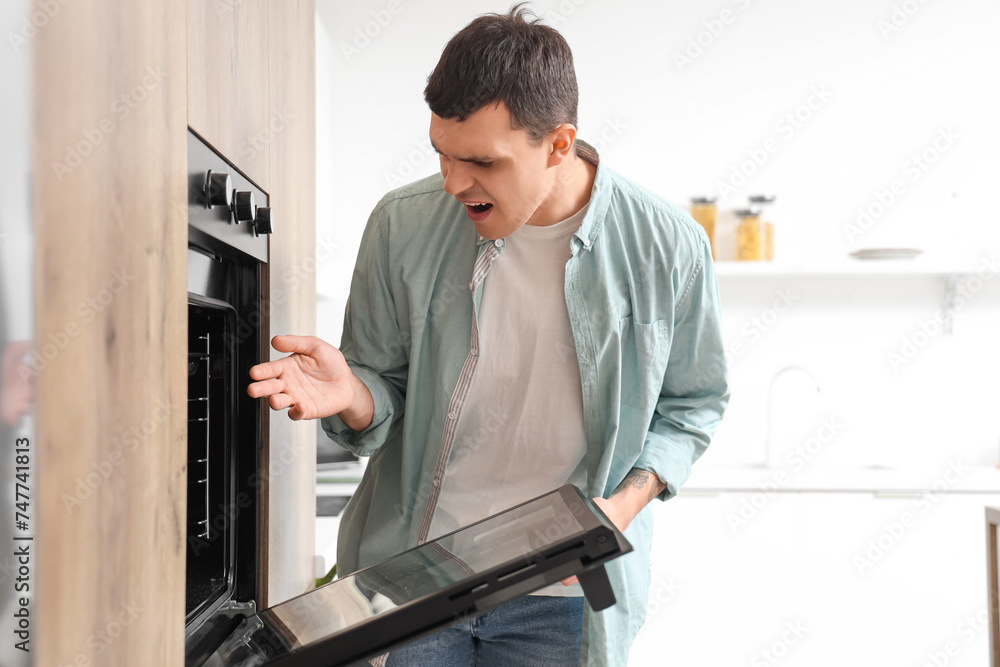 Young man burned his hand on hot oven in kitchen. Trauma concept Young man burned his hand on hot oven in kitchen. Trauma concept