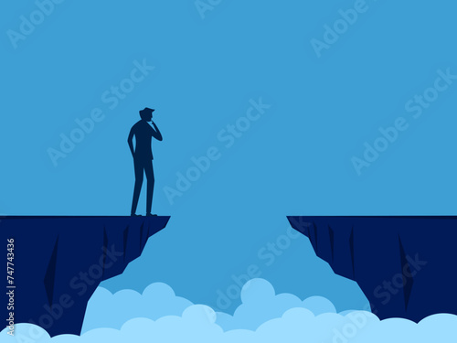Businessman standing and thinking on a high cliff gap photo