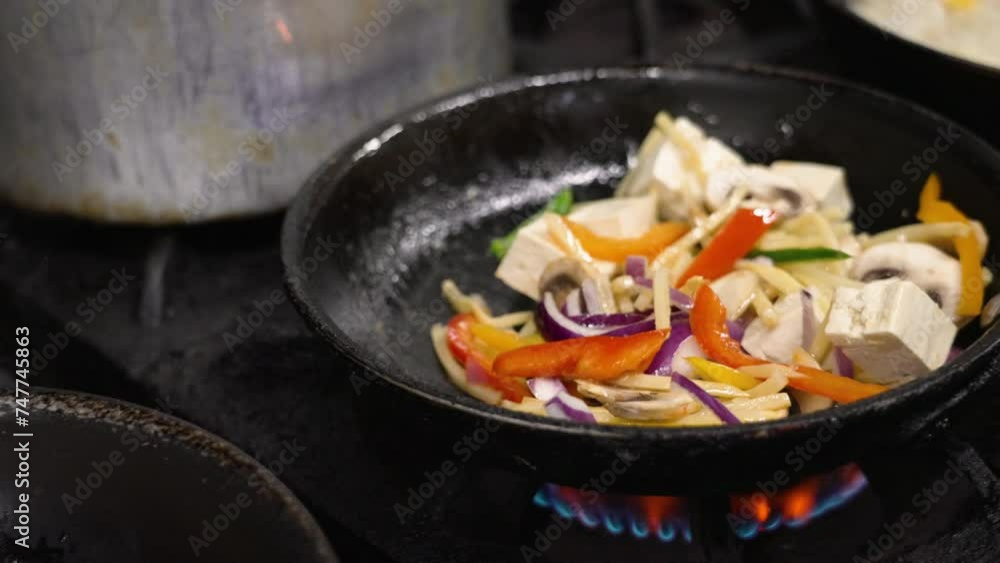 Stirfrying vegetables and tofu over high heat in commercial kitchen, tossing cooking vegetable, slow motion close up 4K Stirfrying vegetables and tofu over high heat in commercial kitchen, tossing cooking vegetable, slow motion close up 4K