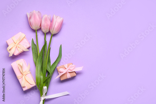 Gift boxes and pink tulips on lilac background. Top view