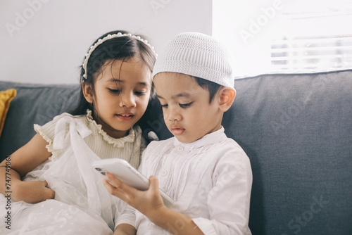 Little kids boy and girl using smartphone together on sofa in the living room