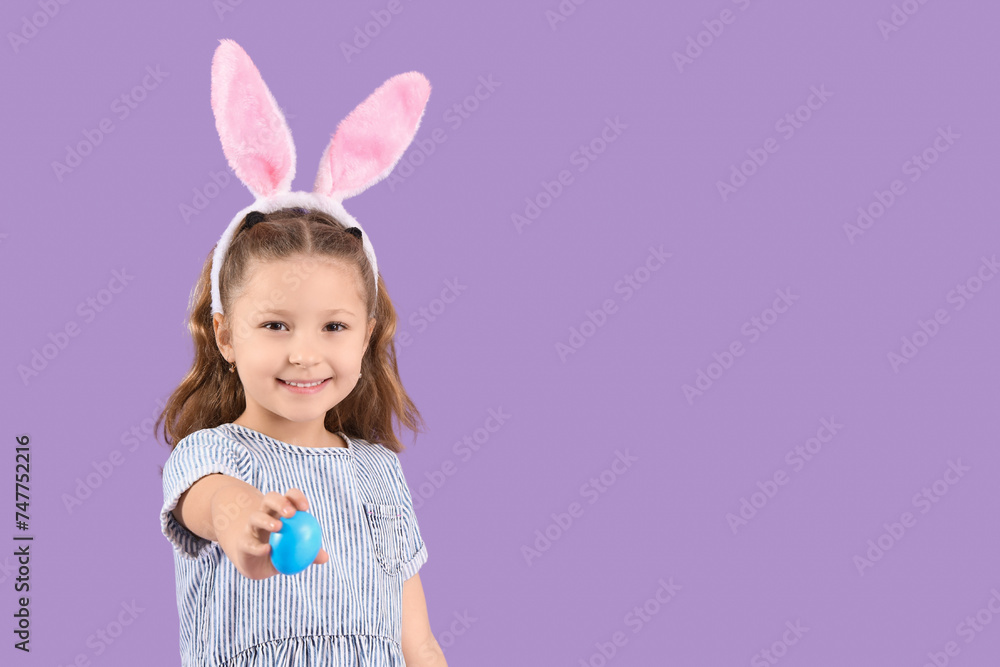 Cute little girl in bunny ears with Easter egg on purple background