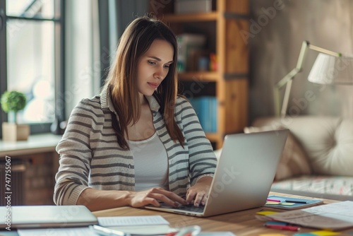 Mujer concentrada trabajando en su portátil en un ambiente de oficina en casa, rodeada de documentos y artículos de trabajo photo