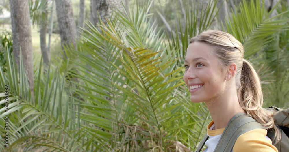 A young Caucasian woman smiles while exploring a lush outdoor setting with copy space A young Caucasian woman smiles while exploring a lush outdoor setting with copy space