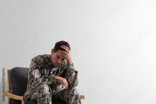 Stressed military officer sitting in armchair on white background. Space for text
