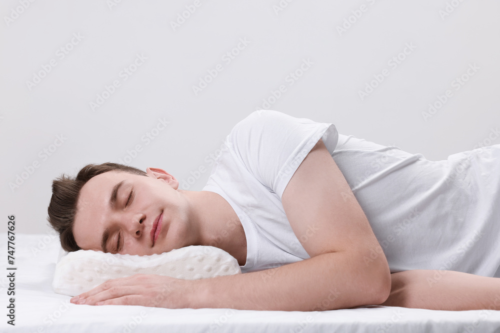 Man sleeping on orthopedic pillow against light grey background Man sleeping on orthopedic pillow against light grey background