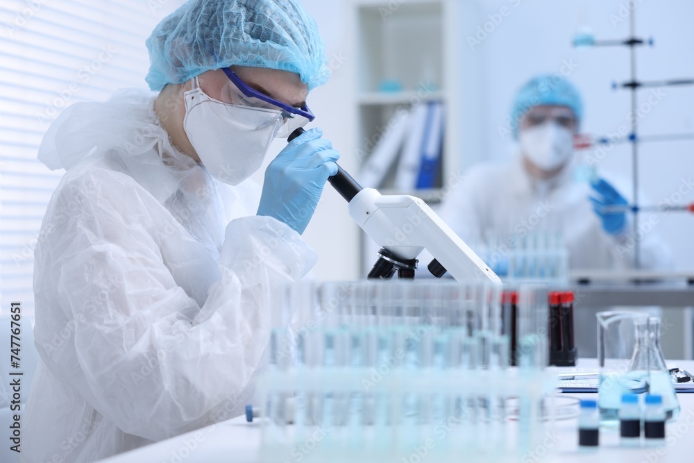 Scientist working with samples and microscope in laboratory Scientist working with samples and microscope in laboratory