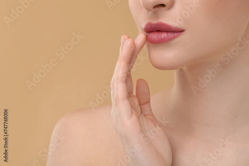 Young woman with beautiful full lips on beige background  closeup