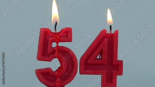 close up on timelapse melting a red number fifty fourth birthday candle on a white background.
 photo