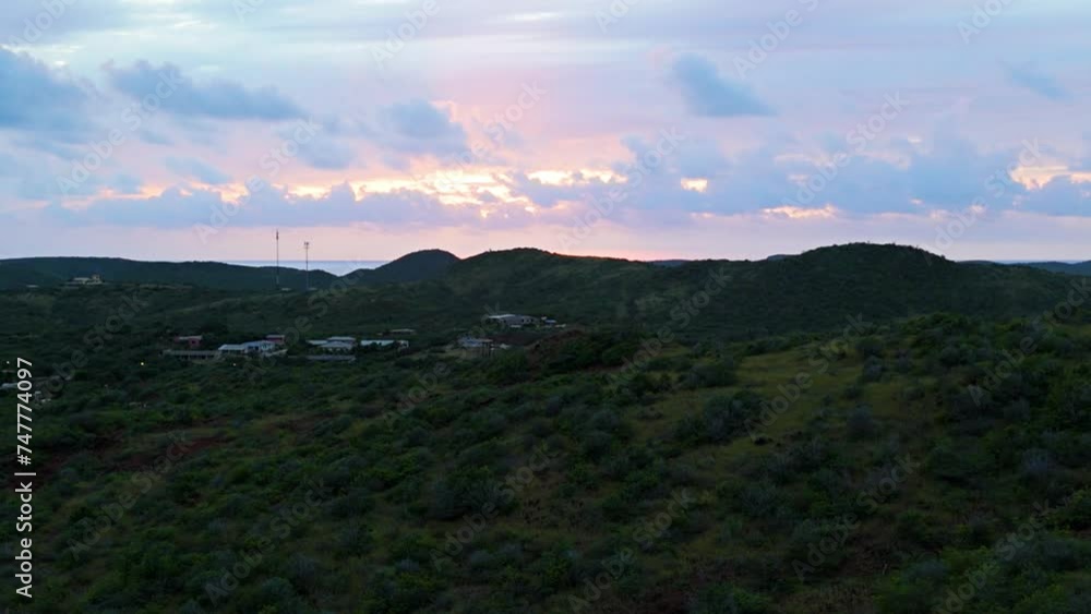 Sunset glow breaks between clouds on Caribbean sea with Curacao nature hiking hills on leeward coast Sunset glow breaks between clouds on Caribbean sea with Curacao nature hiking hills on leeward coast
