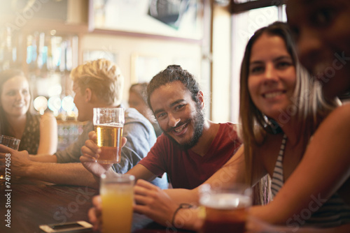 Friends, man and smile in pub with beer for happy hour, relax or social event with confidence. Diversity, people and drinking alcohol in restaurant or club with discussion for bonding and celebration photo