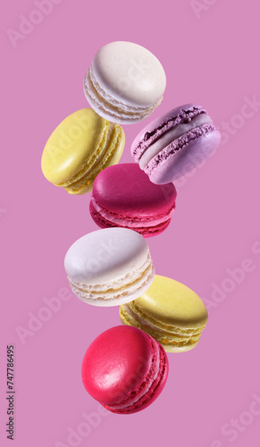 Colorful macaroons falling on pink background