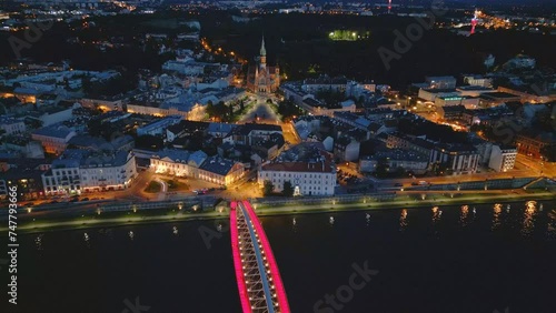 Krakow Podgorze aerial view from drone during night. Illuminated Polish city after sunset.  Kladka Bernatka bridge over Vistula river. photo