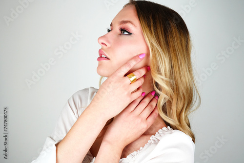Brunette Woman with Blue Eyes Showcasing Elegant Gold Ring on White Background
