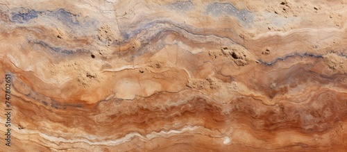 A close-up view of a brown and black marble surface, showcasing intricate patterns and textures. The marbles are rich in color, with a mix of brown and black tones creating a striking contrast.