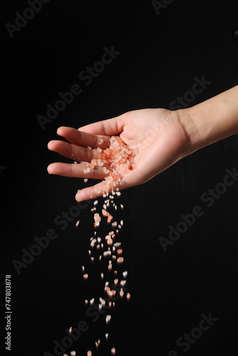 Hand holding pink salt on black background