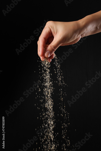 Hand sprinkling brown sugar on black background
