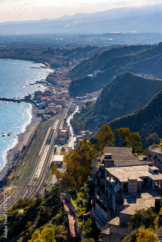 Panoramic view of Taormina shore at Ionian sea with Giardini Naxos and Villagonia towns and Mount Etna volcano in Messina region of Sicily in Italy