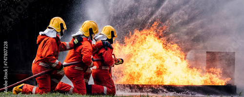 Firefighter Concept. Several firefighters go offensive for a fire attack. Fireman using water and extinguisher to fighting with fire flame.