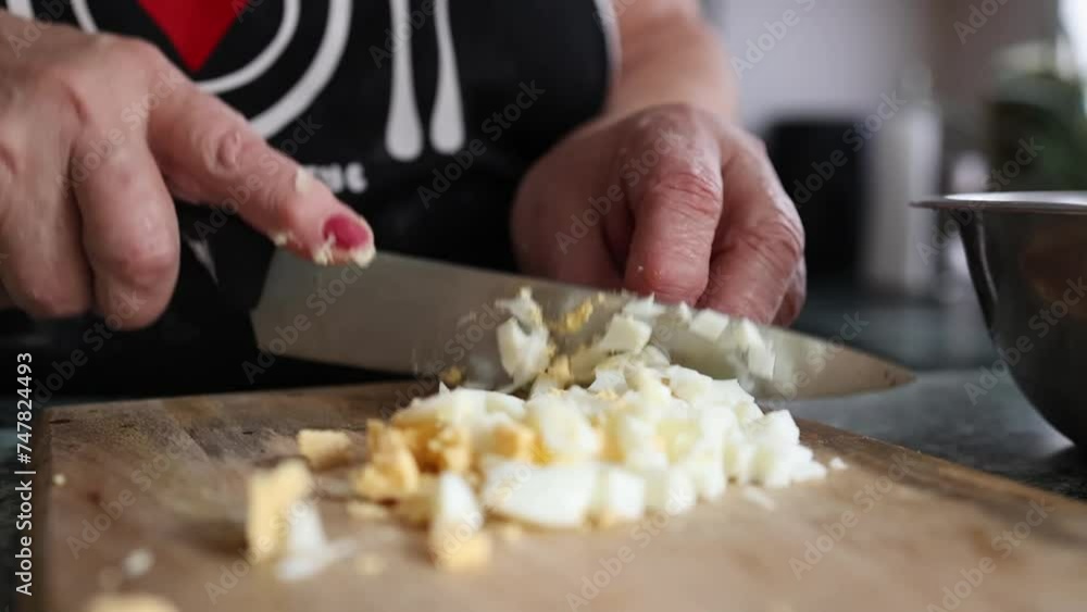 grandmother cuts boiled eggs on a wooden tray. close-up grandmother cuts boiled eggs on a wooden tray. close-up