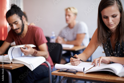 People, students and classroom with books for thinking, info and solution with education, studying and ideas. Man, woman and learning for exam with notes, pen and reading for development at college
