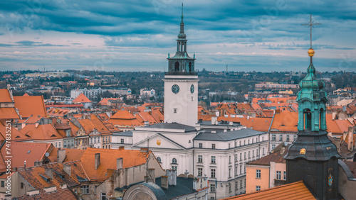 illuminated night view of the town hall in Kalisz, Poland from a drone, dramatic blue sky before rain, view of old tenement houses and architecture