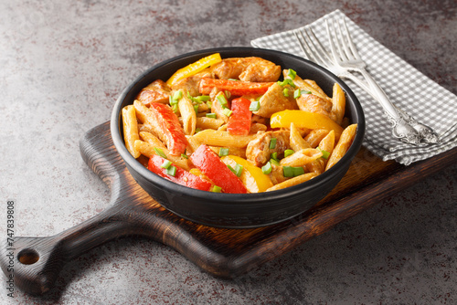 Jamaican Style Rasta Pasta Penne with Grilled Chicken and Bell Peppers closeup on the bowl on the wooden board. Horizontal