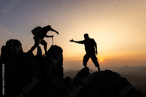 Silhouette of The men helping pull people up from high cliffs.