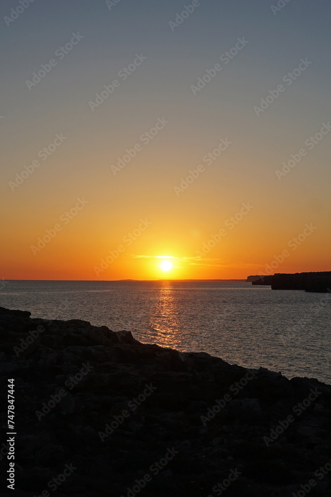 Natural landscape of Playa de Cavalleria (Mercadal) in Minorca beach with sunset sky and rocky seashore- Menorca, Spain