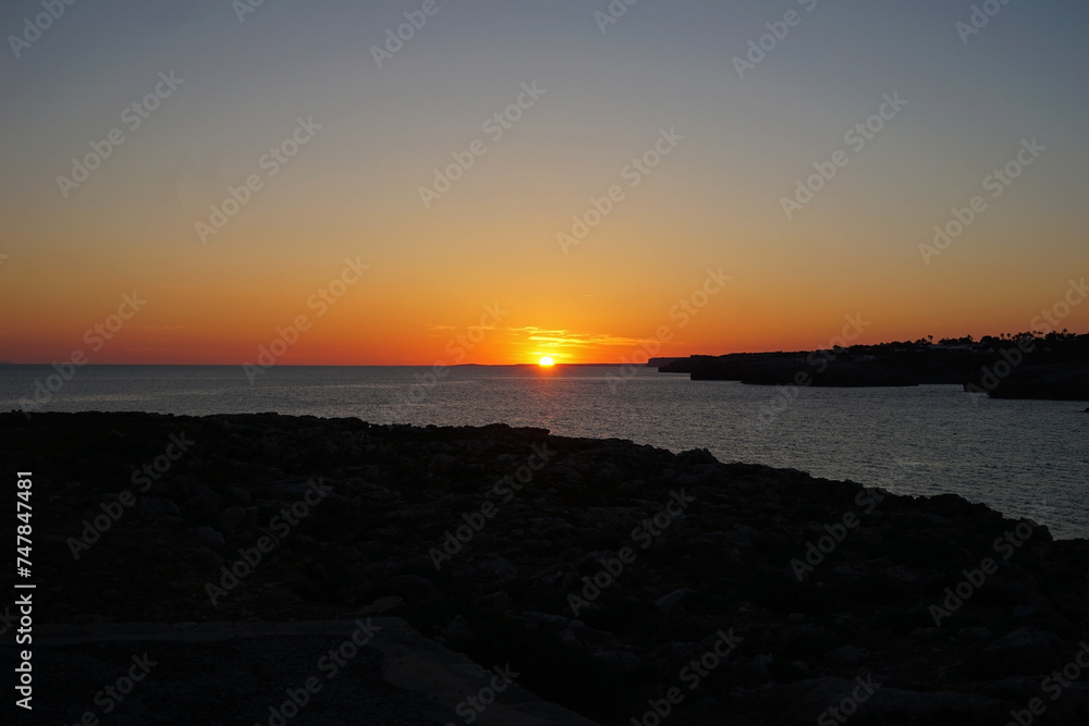 Natural landscape of Playa de Cavalleria (Mercadal) in Minorca beach with sunset sky and rocky seashore- Menorca, Spain