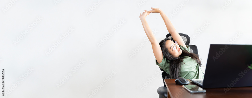 Happy relaxed young woman sitting in her kitchen with laptop in front of her, stretching her arms above her head and looking out the window. Happy relaxed young woman sitting in her kitchen with laptop in front of her, stretching her arms above her head and looking out the window.