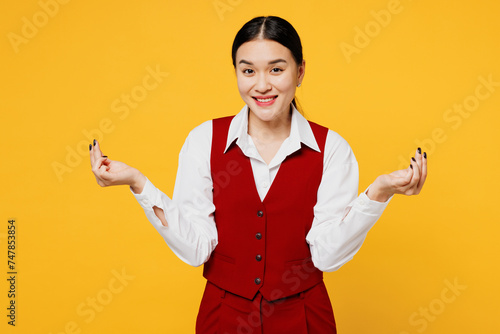 Young corporate lawyer employee business woman of Asian ethnicity wear formal red vest shirt work at office rub fingers show cash gesture ask money isolated on plain yellow background. Career concept.