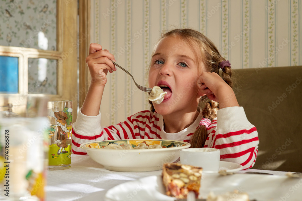Hungry girl eats homemade dumplings dipped in sour cream. Enjoyment of dish and satisfying hunger. Spending holidays in village in summer Hungry girl eats homemade dumplings dipped in sour cream. Enjoyment of dish and satisfying hunger. Spending holidays in village in summer