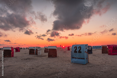 Wicker beach chairs on the sand beach of Neuharlingersiel at sunset, North Sea, East Frisia, Lower Saxony, Germany
