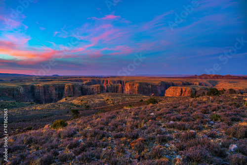 Sunset over Dead Indian Canyon in Arizona with vibrant sky and rugged cliffs. It is situated in the Paria Canyon-Vermilion Cliffs Wilderness and is known for its unique geological formations.
