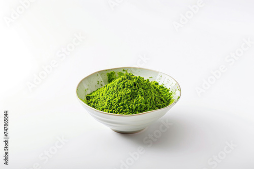 A bowl of vibrant green matcha powder on a white surface