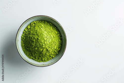 A bowl of vibrant green matcha powder on a white surface