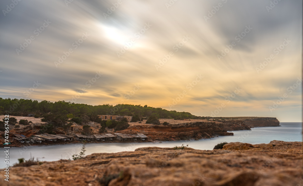 Long exposure of a cove in Formentera with fishermen's boats and cotton clouds